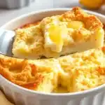 Freshly baked Lemon Cream Cheese Dump Cake in a white ceramic dish, with a golden crumb topping, creamy filling, and lemon slices beside it.